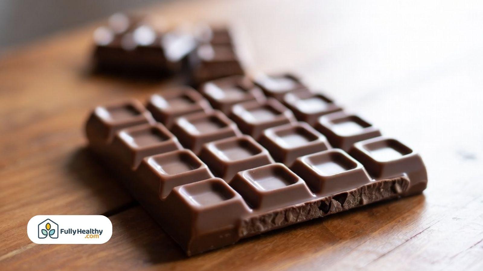 Milk chocolate bar pieces arranged on a wooden table.