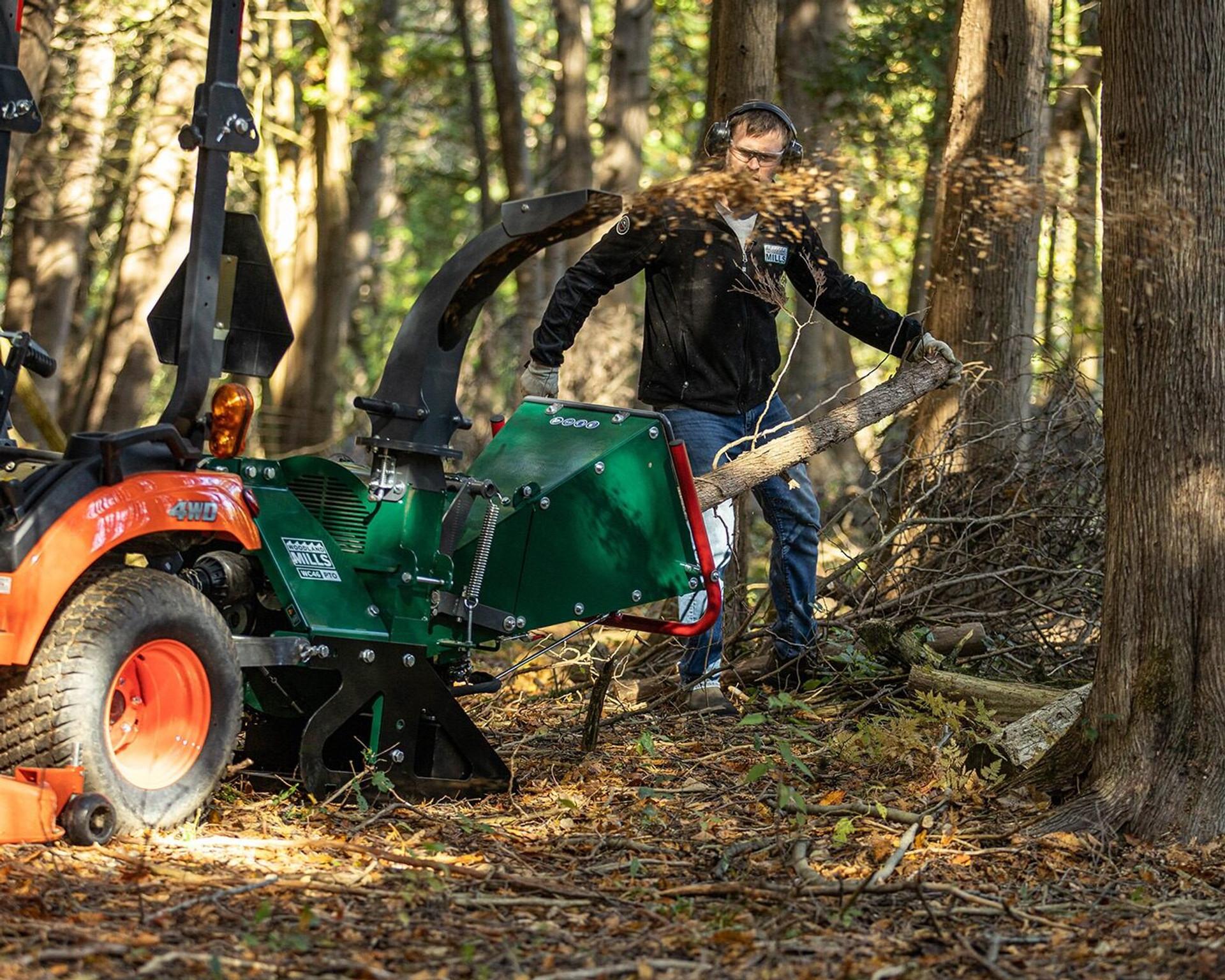 A man feeding a tree trunk into a Woodland Mills wood chipper.
