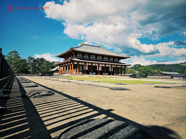 A imagem retrata o Grande Salão de Buda (Daibutsuden) do Templo Kofuku-ji em Nara, Japão. Esta estrutura histórica com seu telhado imponente e pilares vermelhos é um dos edifícios principais do complexo do templo, situado sob um céu azul com nuvens brancas, com montanhas ao fundo.




