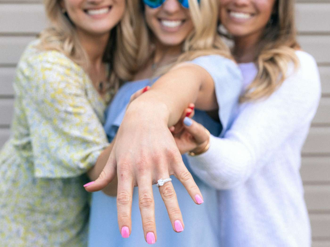 A newly engaged woman showcases her sparkling ring, surrounded by friends celebrating her joyous moment, a symbol of love and commitment that resonates with the essence of the Engagement Flowers Collection by Fabulous Flowers and Gifts.