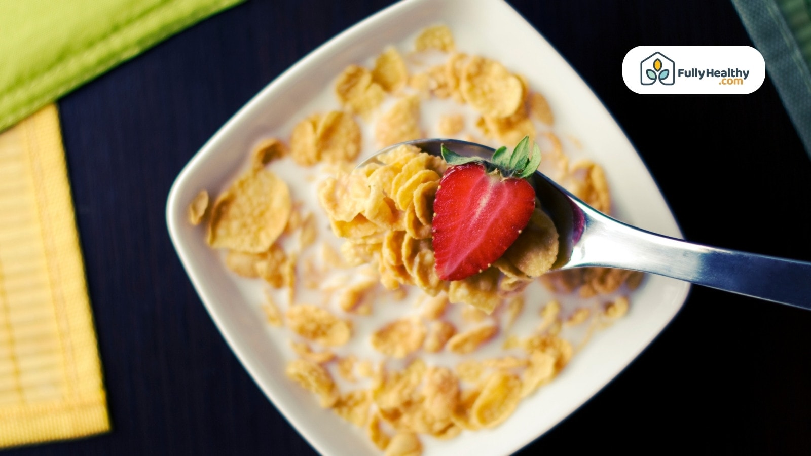 Cornflakes with milk and fresh strawberry slice on silver spoon