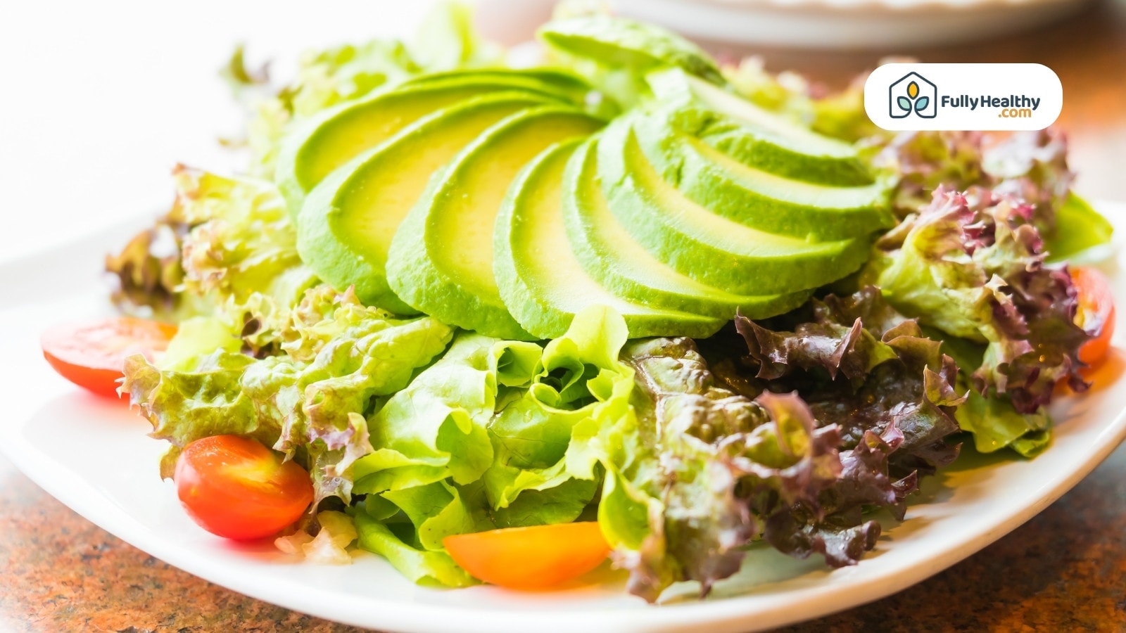 Fresh salad with sliced avocado lettuce and cherry tomatoes on plate