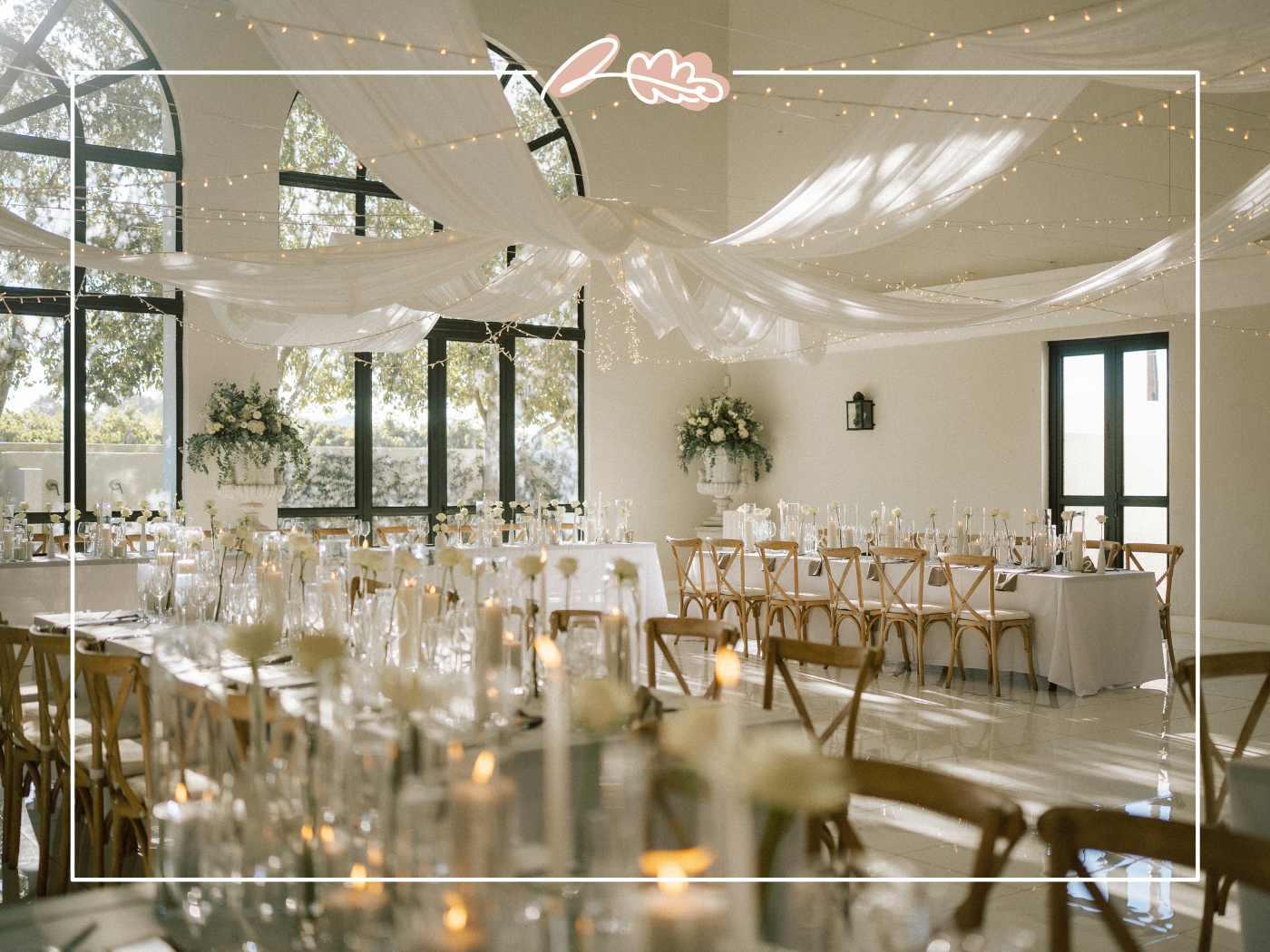 Nantes Estate reception room styled with white draped fabric, fairy lights and white floral arrangements for Tess and Greg's wedding