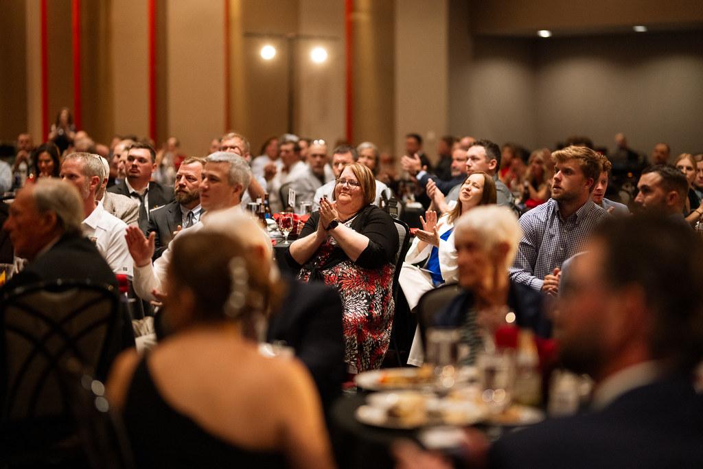 The image depicts a formal construction awards gala taking place at the Sharonville Convention Center, where contractors and builders are networking and engaging in conversations. This annual event celebrates excellence in construction and honors the achievements of the Ohio Valley chapter, fostering community and leadership within the industry.