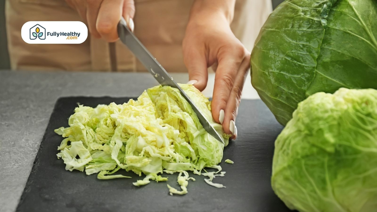 Person chopping fresh cabbage into thin slices on board