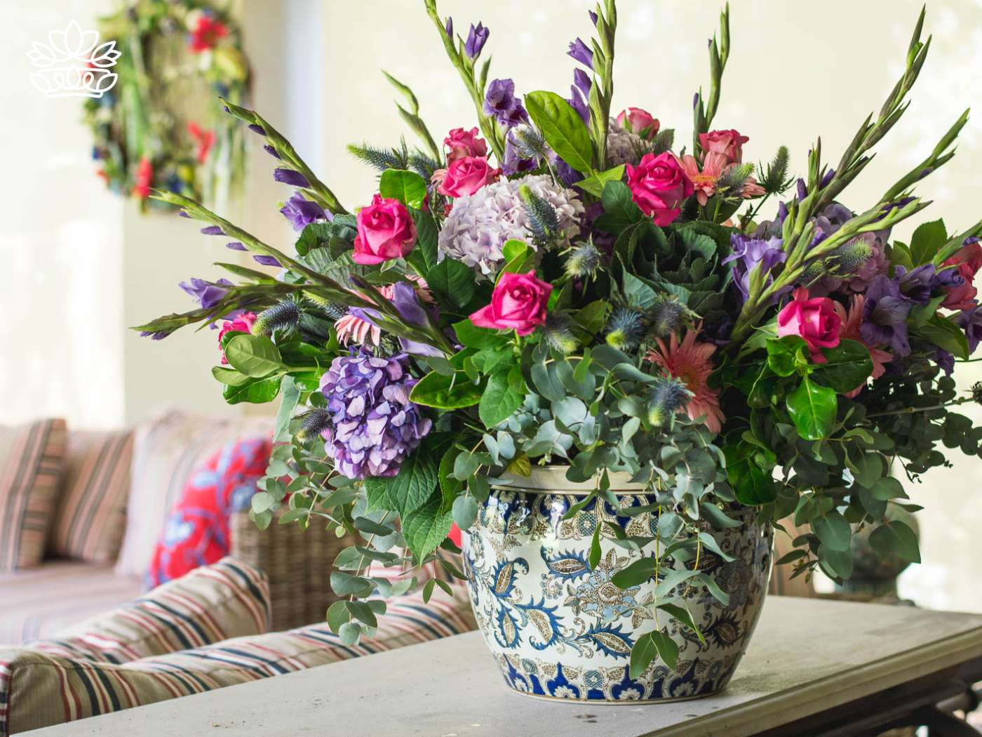 Exquisite porcelain vase overflowing with an arrangement of fresh pink roses, purple blooms, and lush greenery, a signature piece from Fabulous Flowers and Gifts.
