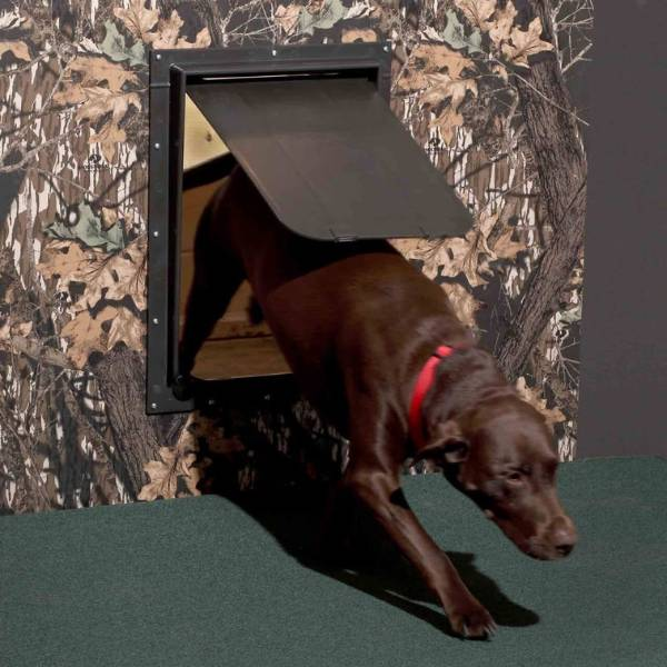 A dark brown pet door with a dog passing through, set against a camouflage-patterned wall, demonstrating how to install dog doors in a door