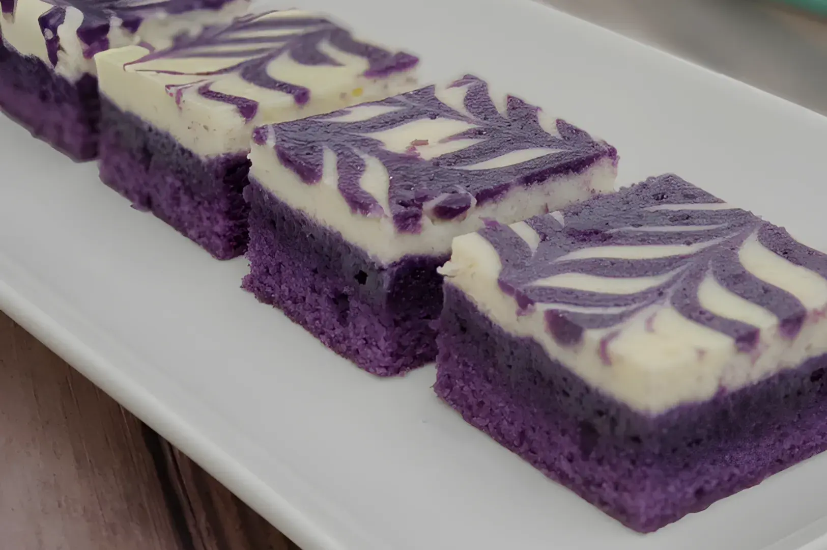 A plate of purple-hued layered cake slices with a swirled cream topping.