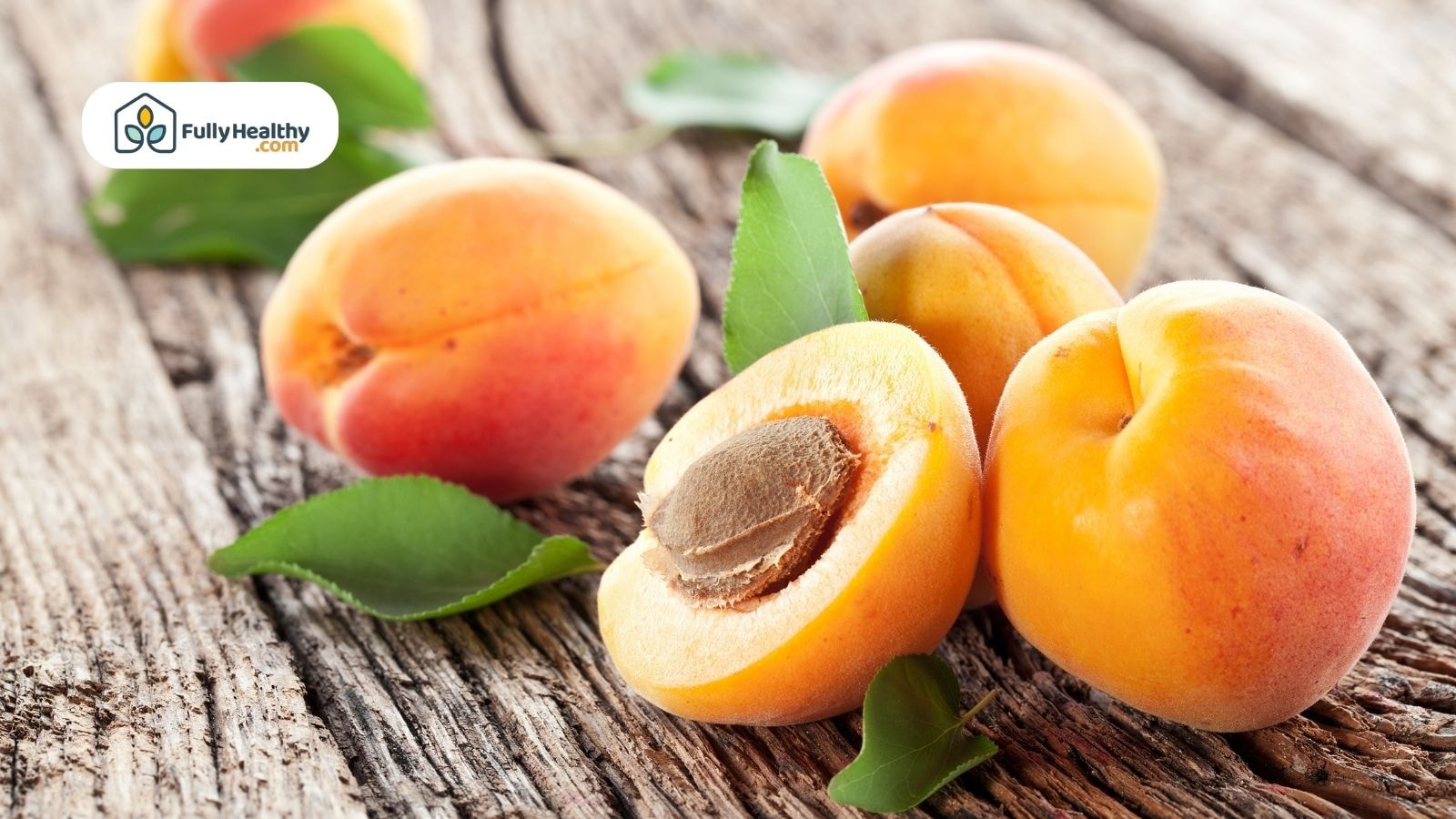 Fresh apricots on a wooden table with a visible pit