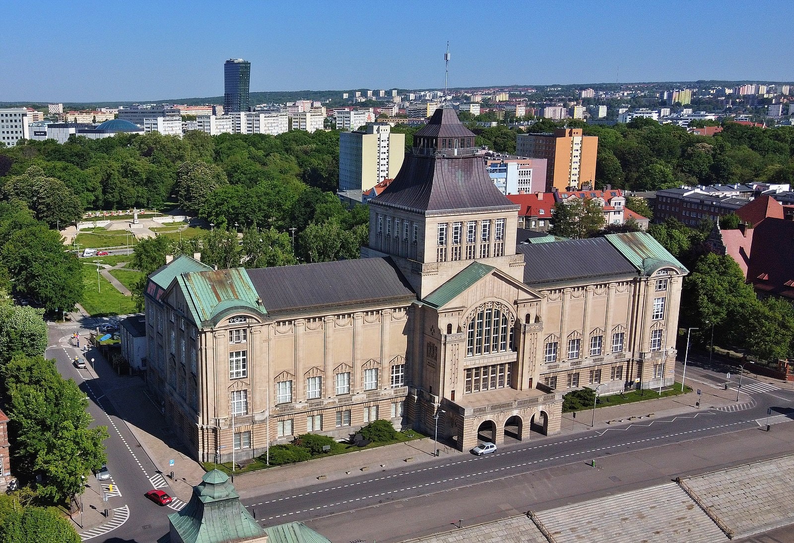 Widok z góry na potężny budynek w szarym kolorze, który należy do Muzeum Narodowego w Szczecinie. Źródło: https://commons.wikimedia.org/wiki/File:Szczecin_Waly_Chrobrego_muzeum_dron_%281%29.jpg