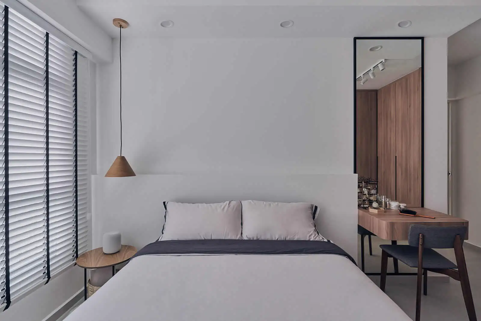 Minimalist room with white walls, timber desk and pendant beside a low bed