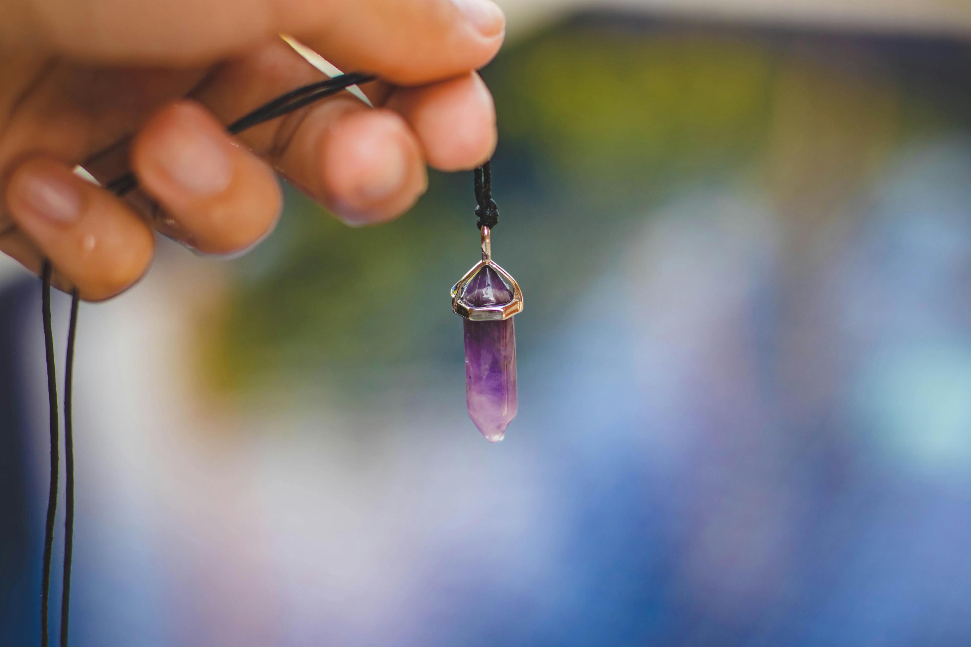 A hand holding a gemstone pendant 