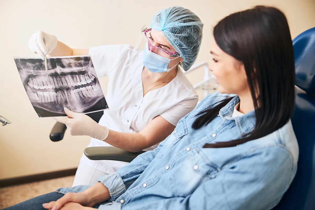 A dental professional showing a patient their dental X-ray during a consultation