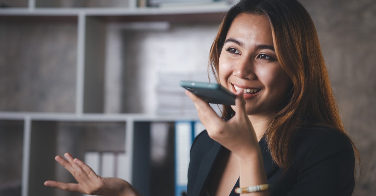 Woman discussing business expense categories on phone in a modern office.