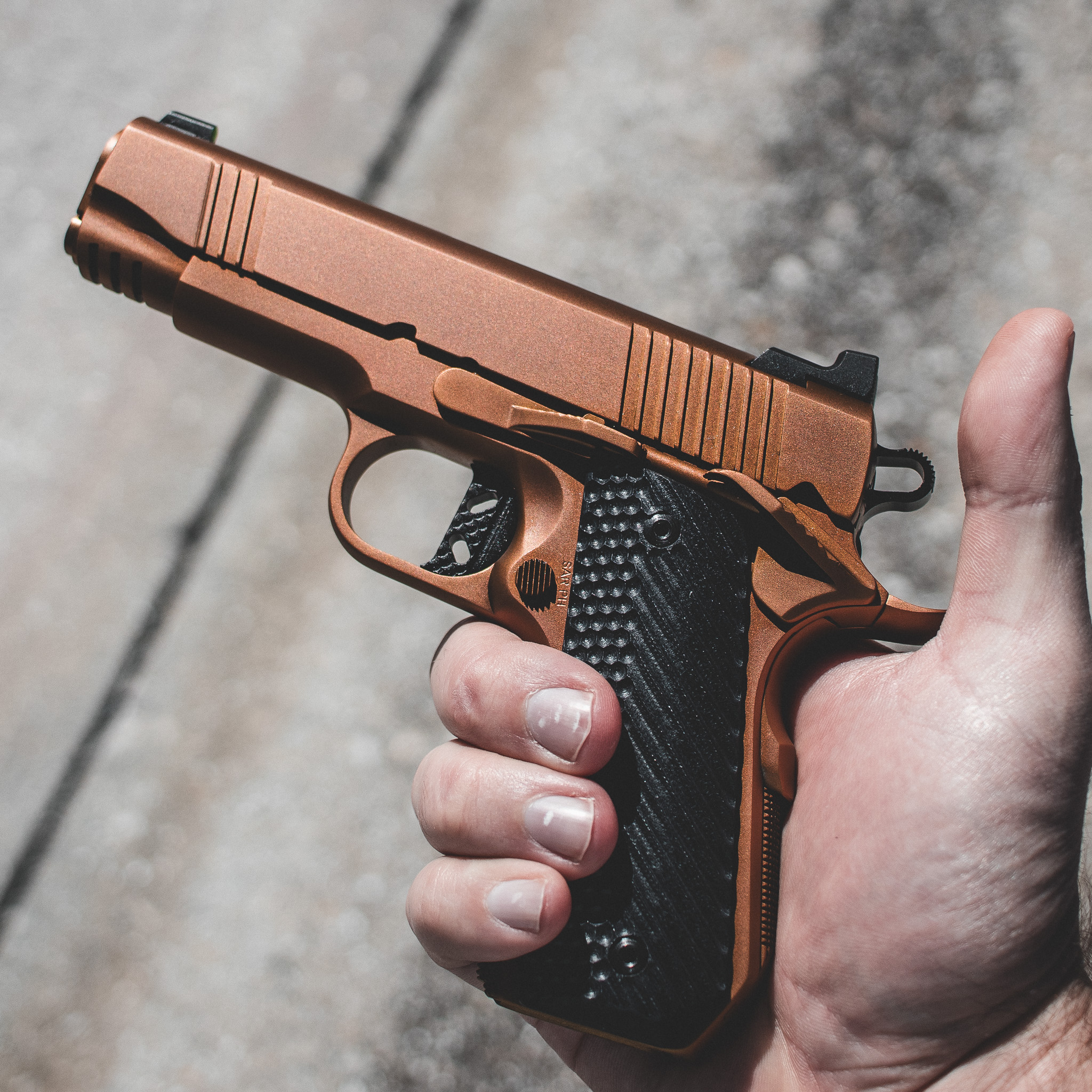 A stylized illustration showing the grip angle and trigger of a 1911 pistol