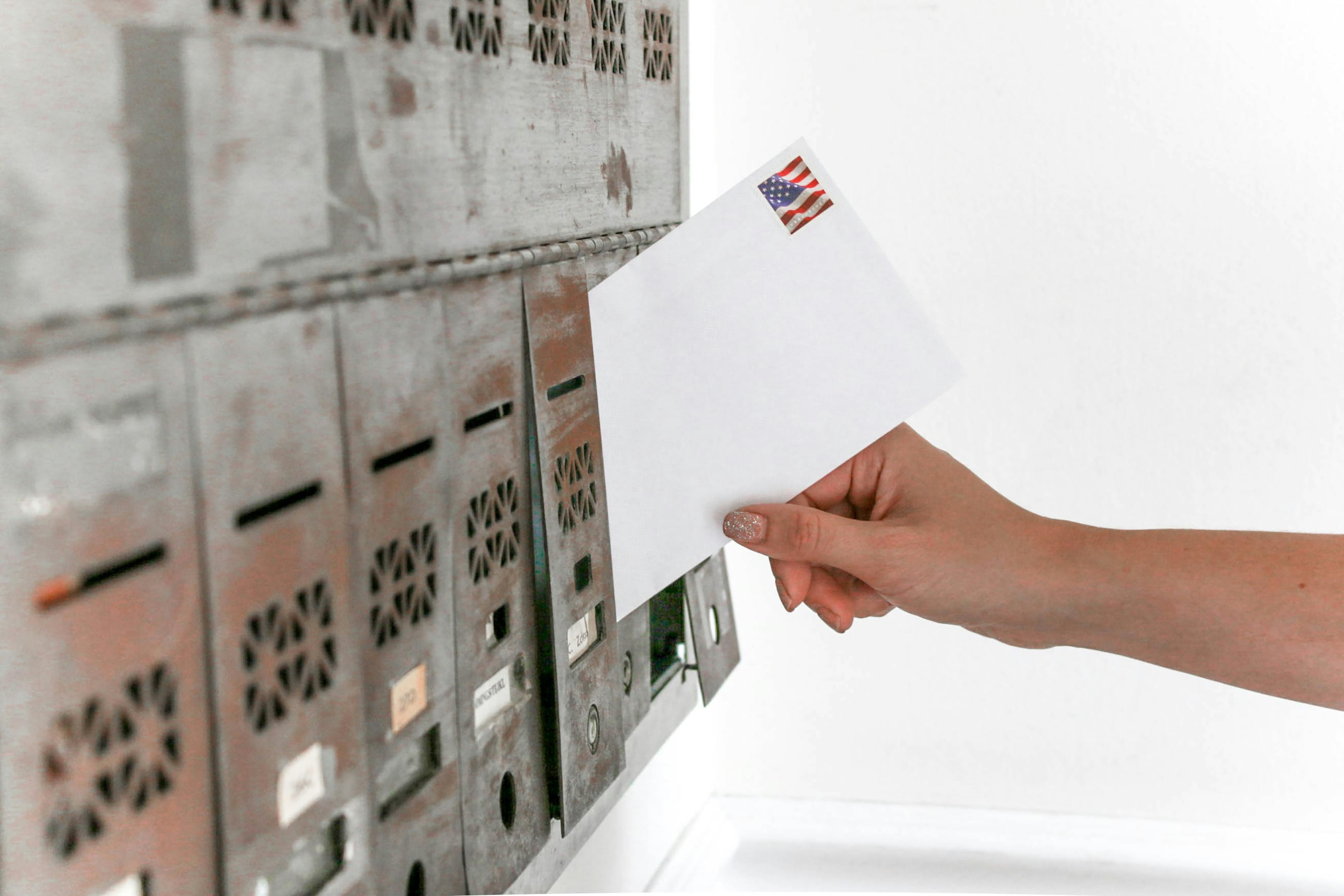 Stamped envelope being put into mailbox. 