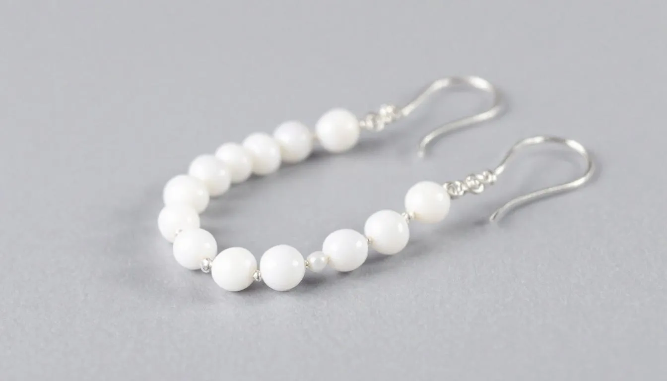 The image showcases a pair of handmade white bead earrings, featuring a delicate combination of seed beads and pearls, elegantly designed with sterling silver hooks. These lightweight beaded earrings add a stylish touch to any wardrobe, perfect for various occasions.
