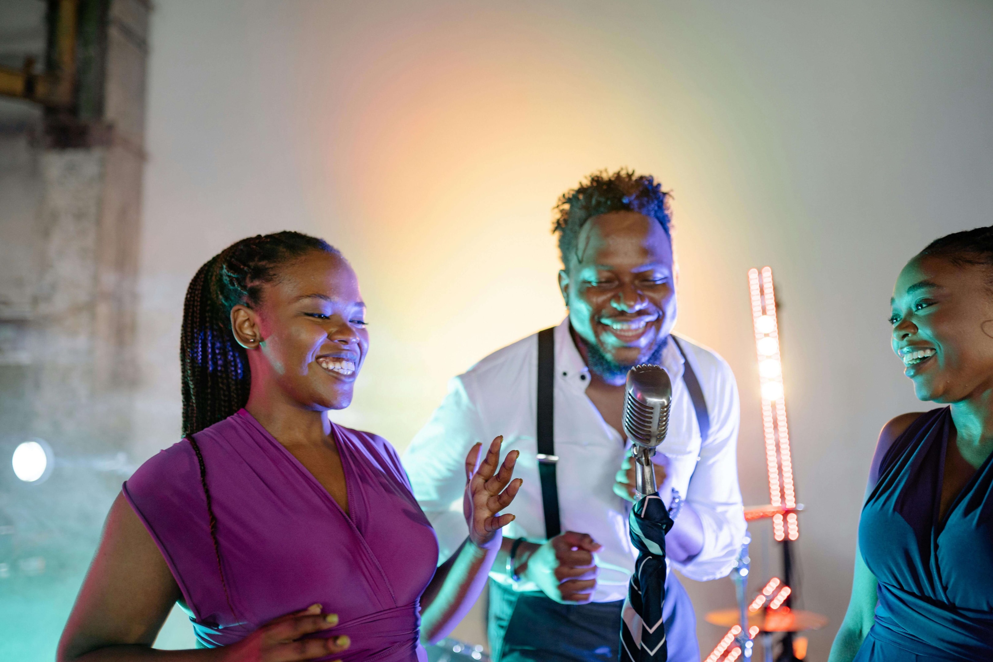 Three individuals singing into a microphone