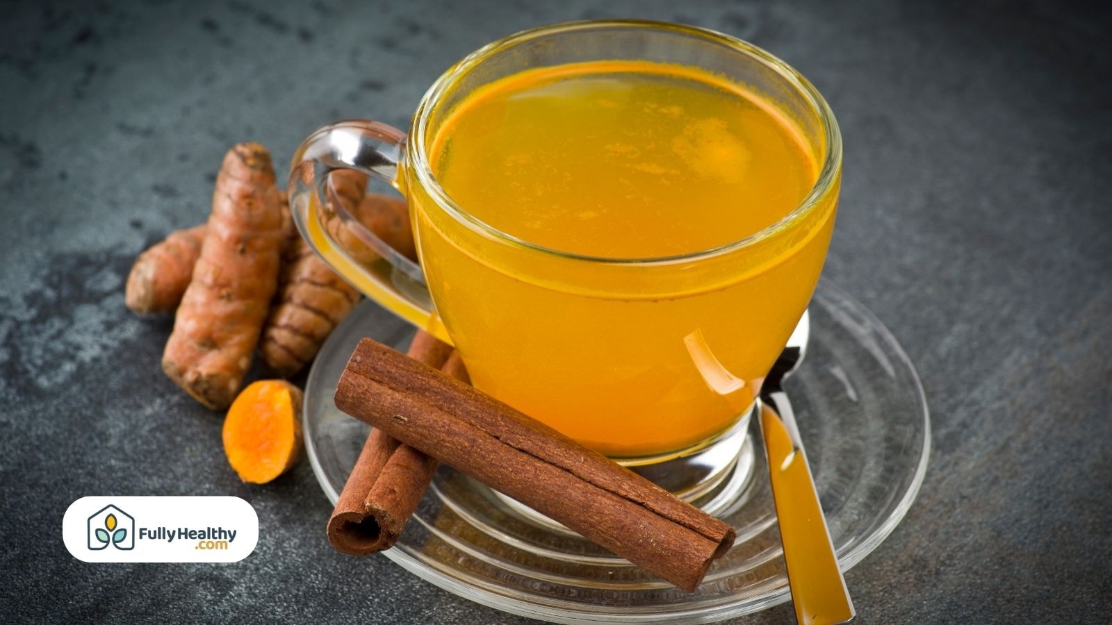 Golden turmeric tea in a glass cup with cinnamon sticks and fresh turmeric root beside it