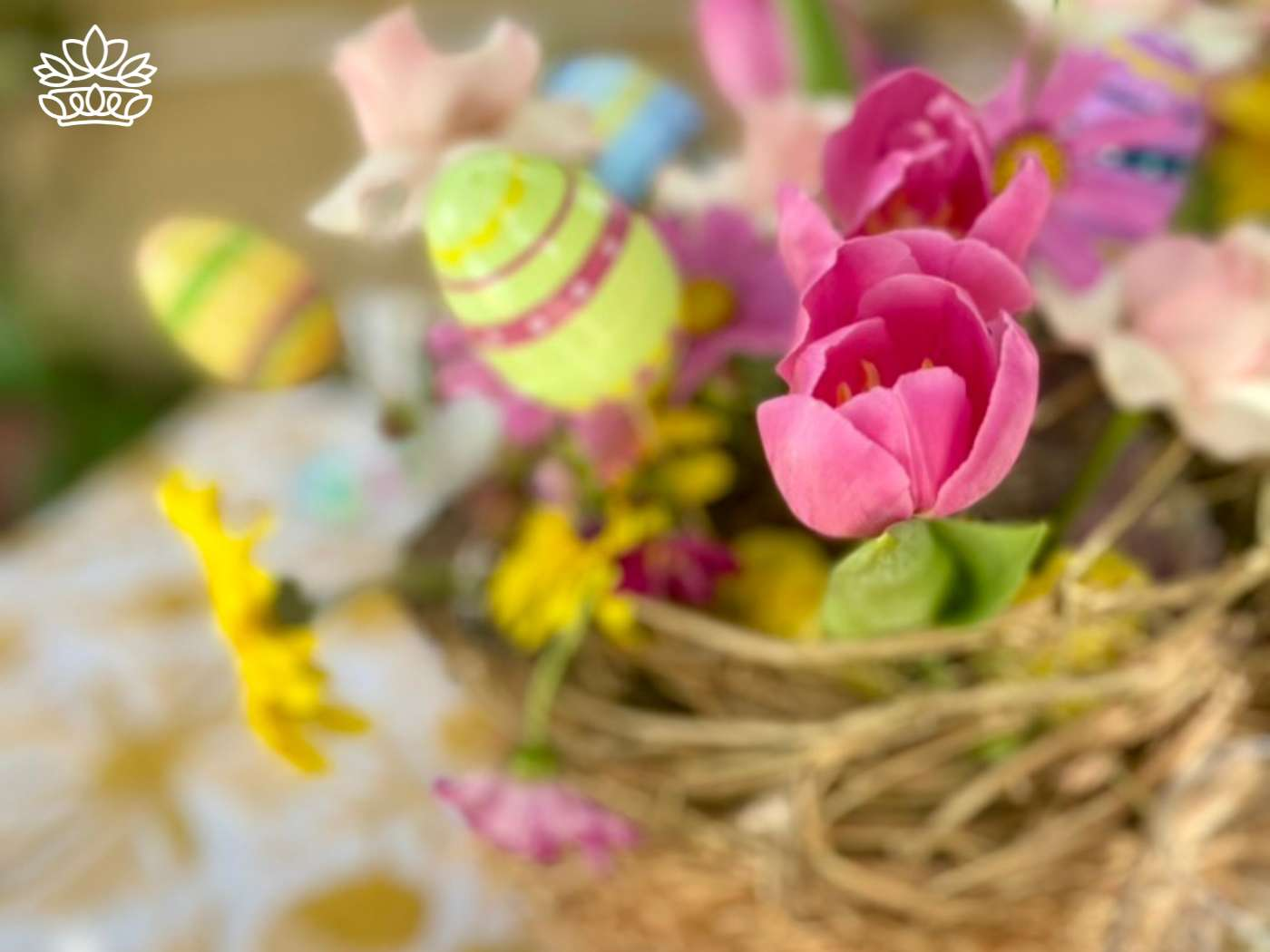 Blurred image of a vibrant Easter basket with pink tulips and festive decorations, including Easter bunny motifs, offering creative Easter basket ideas from the Easter Collection by Fabulous Flowers and Gifts.