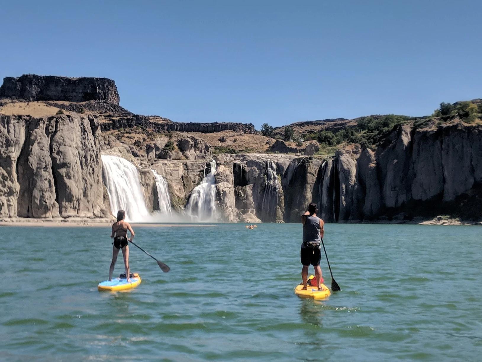 woman on a glide paddle board by a waterfall