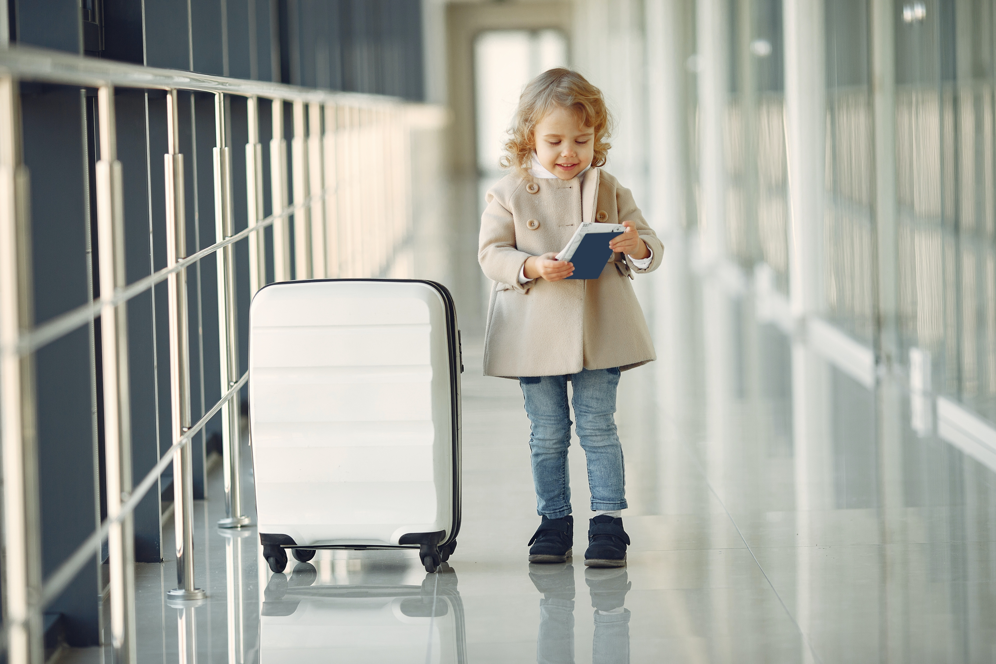 A child with a suitcase in an airport corridor 