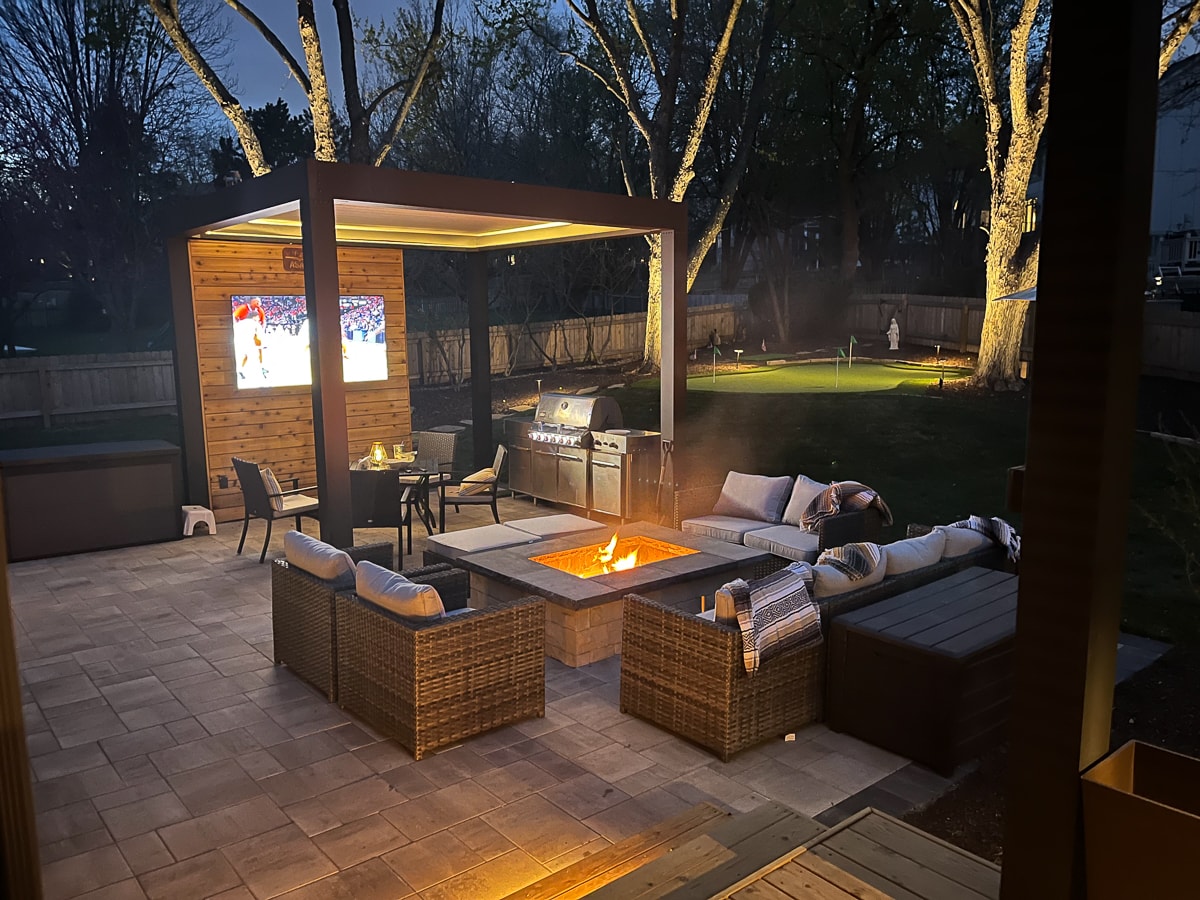 backyard pergola with a cozy seating area and projector screen giving a cozy space to enjoy with company.