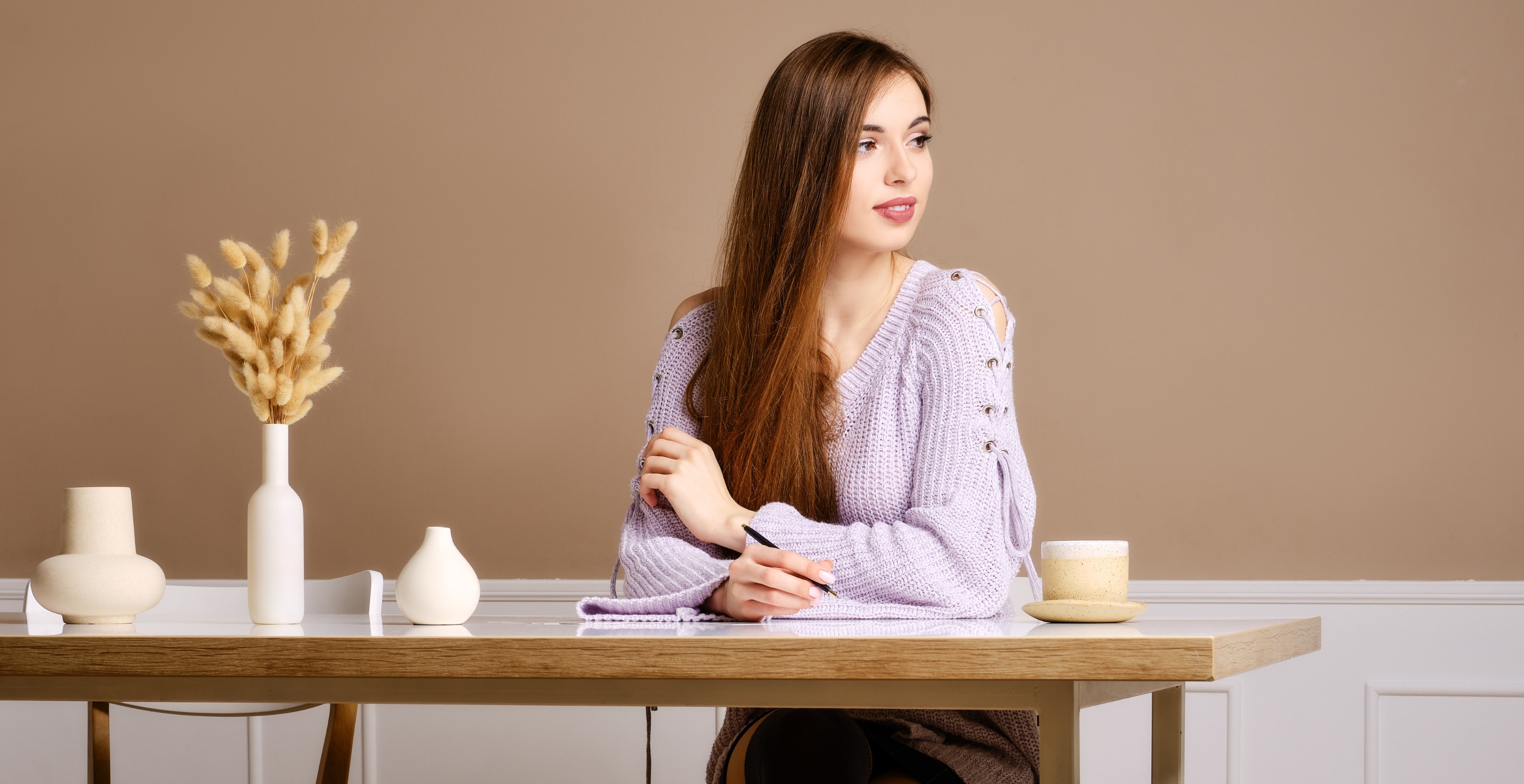 Woman in a lavender sweater writing notes, planning OnlyFans tax write offs at a desk.