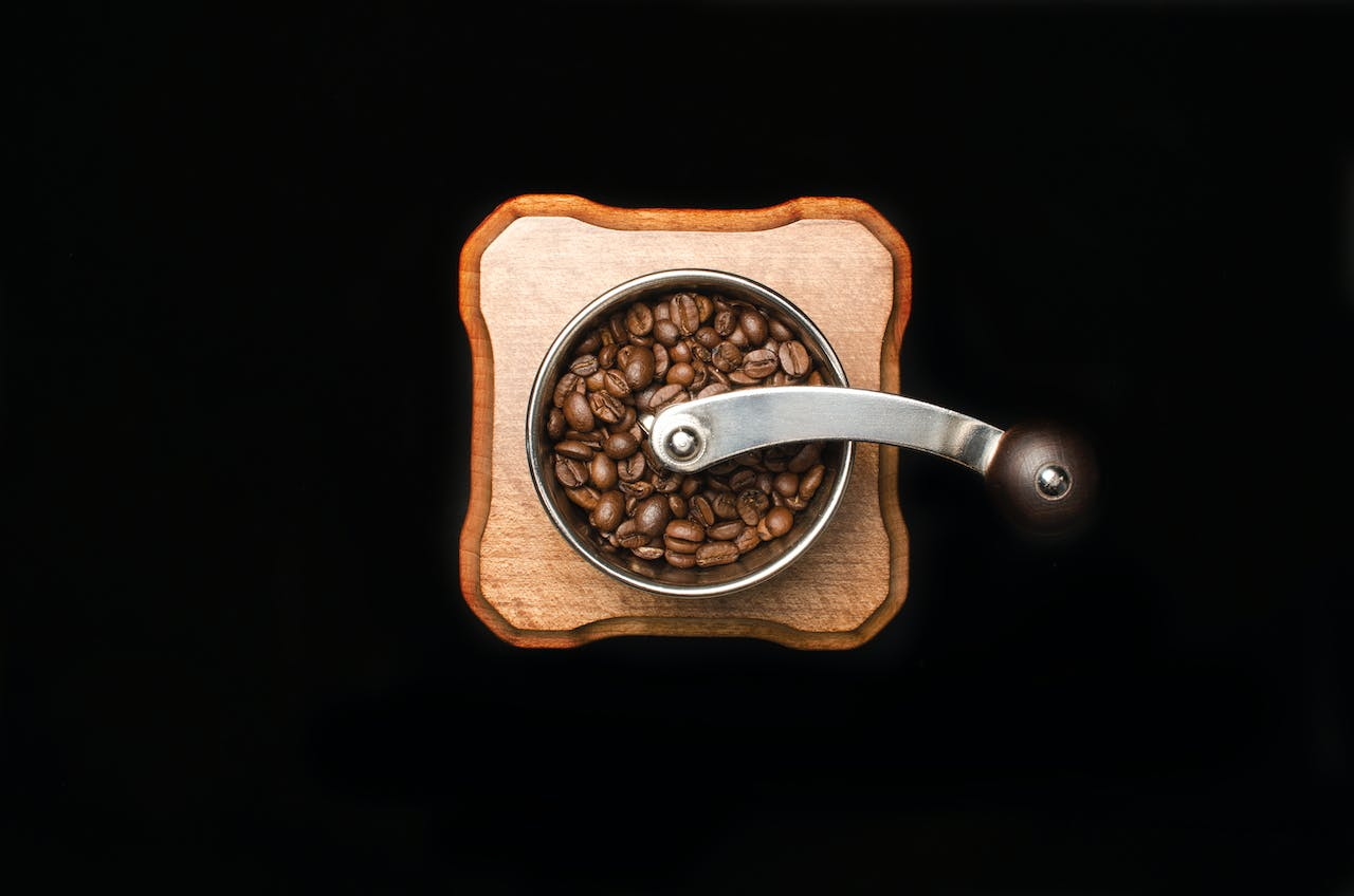 An aesthetic coffee grinder from the top-down on a black background