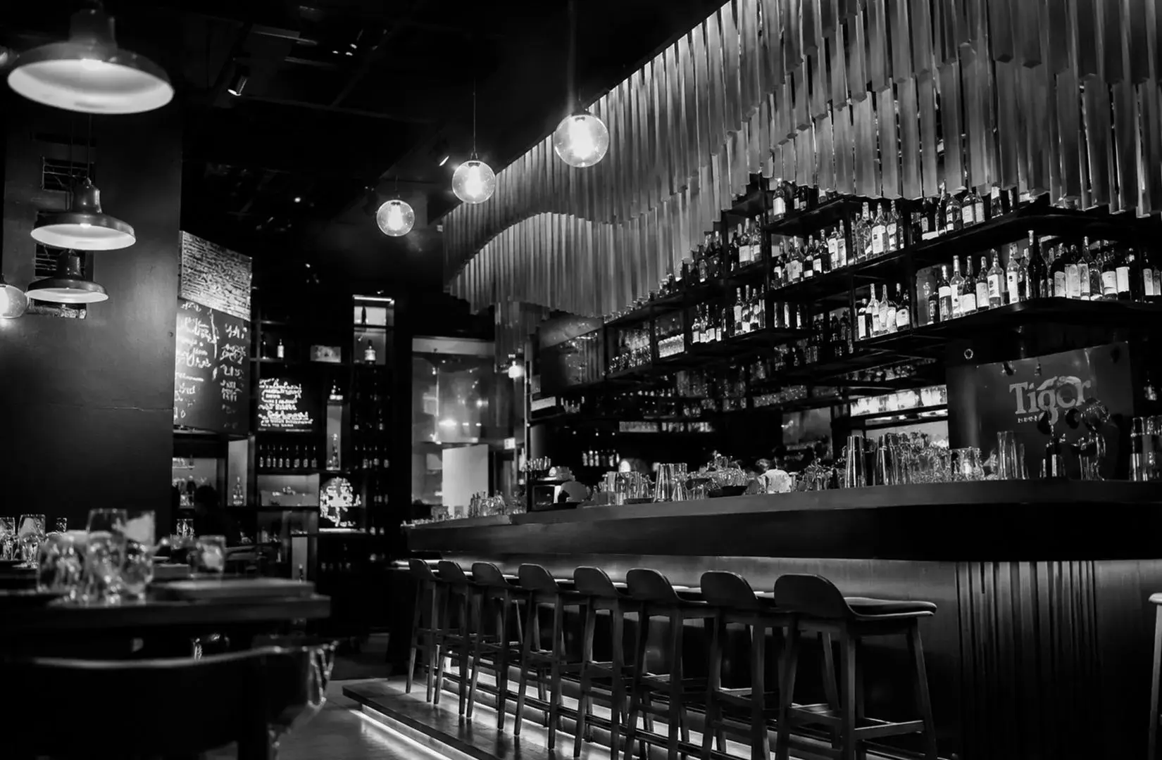 Contemporary interior of The Spot (Marina One) featuring a stylish bar, illuminated shelves, and modern seating.