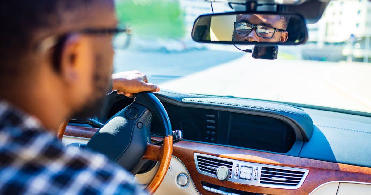 Male schema therapist at the Schema Therapy Training Center of New York, introspectively looking into a rearview mirror, symbolizing self-reflection on unseen aspects of schema therapy supervision.