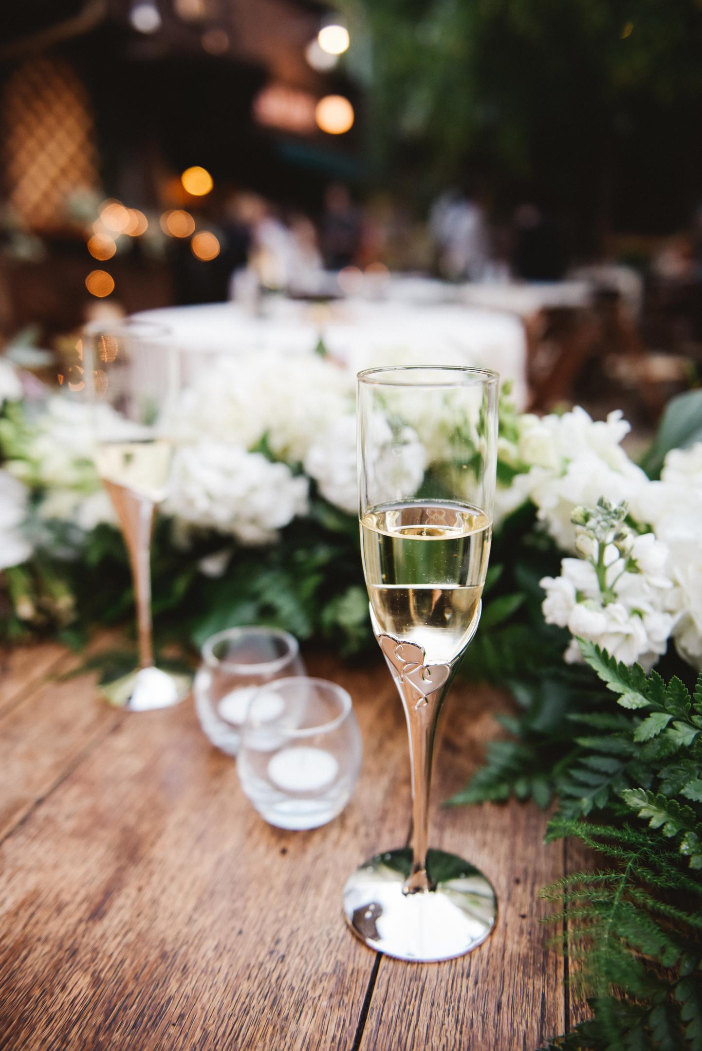 Två glas bubbel omringade av vita blommor på bröllop
