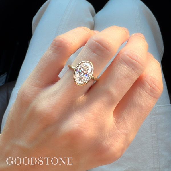A gold oval engagement ring with a diamond in the center and intricate details