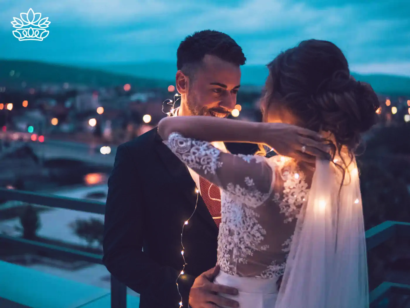 A bride and groom embracing on a rooftop decorated with fairy lights, capturing a magical wedding moment. Fabulous Flowers and Gifts. Romantic Gift Boxes.