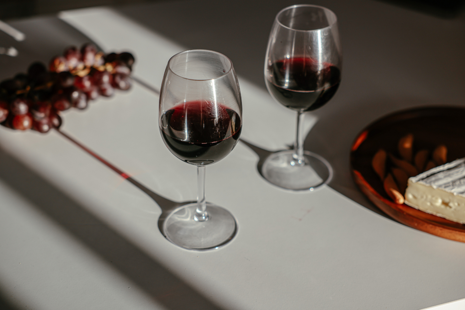 Two glasses of red wine with grapes.