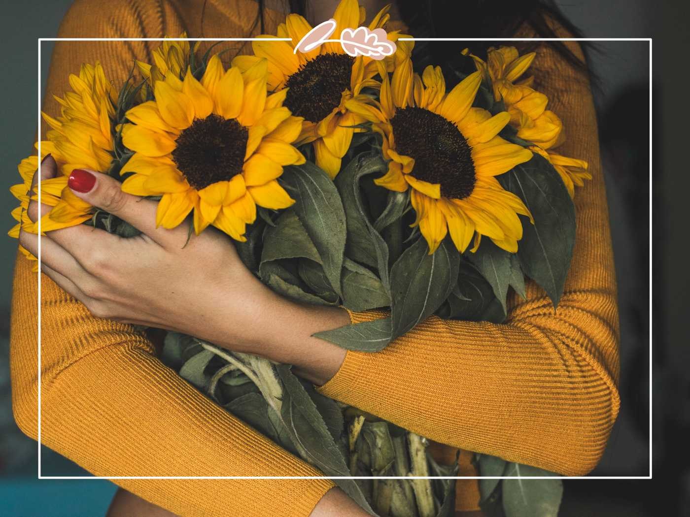 A person holding a bouquet of vibrant sunflowers, symbolizing warmth and happiness - Fabulous Flowers and Gifts.