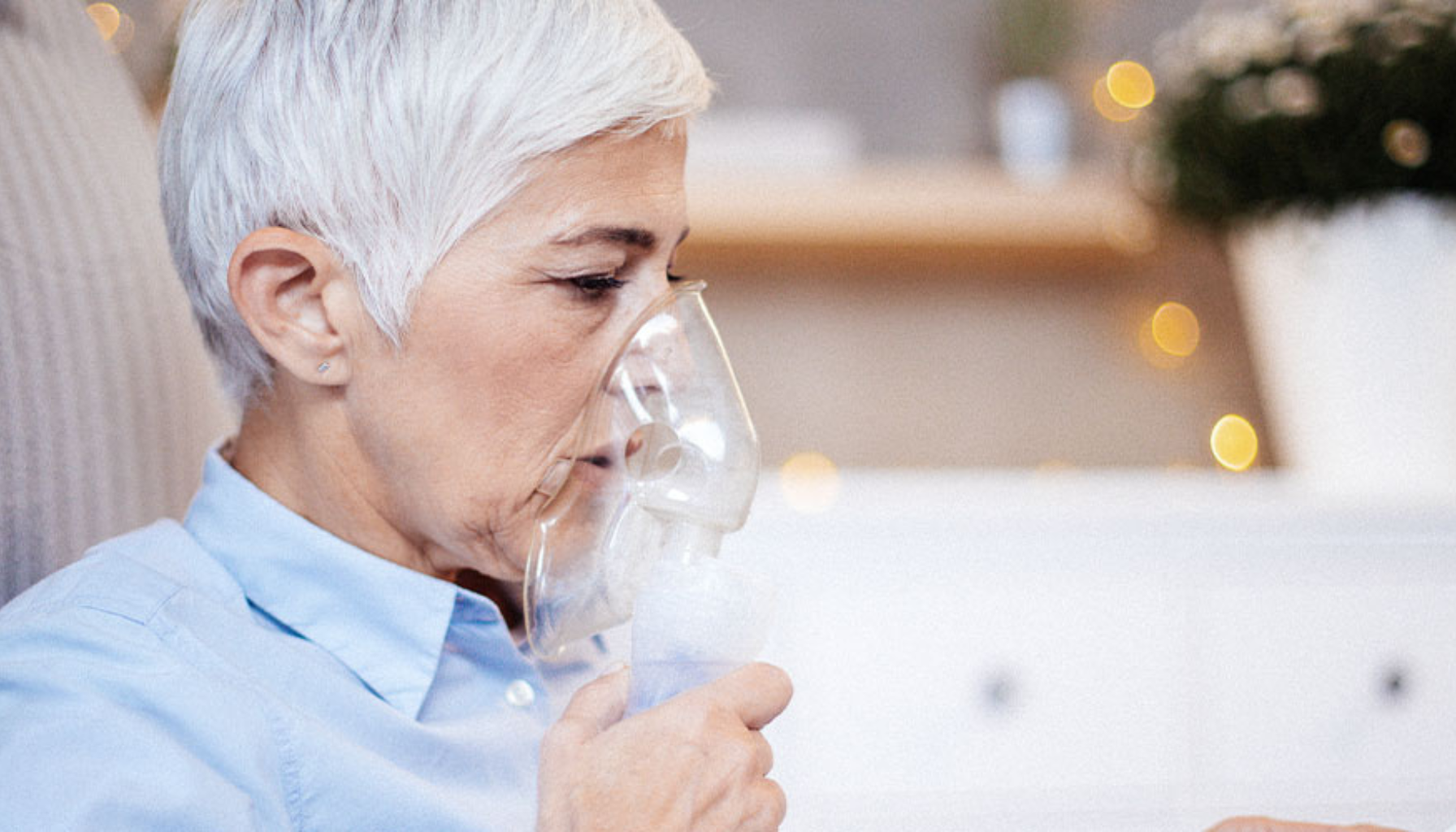 Eldre kvinne bruker forstøvermaske i rolig hjemmemiljø.