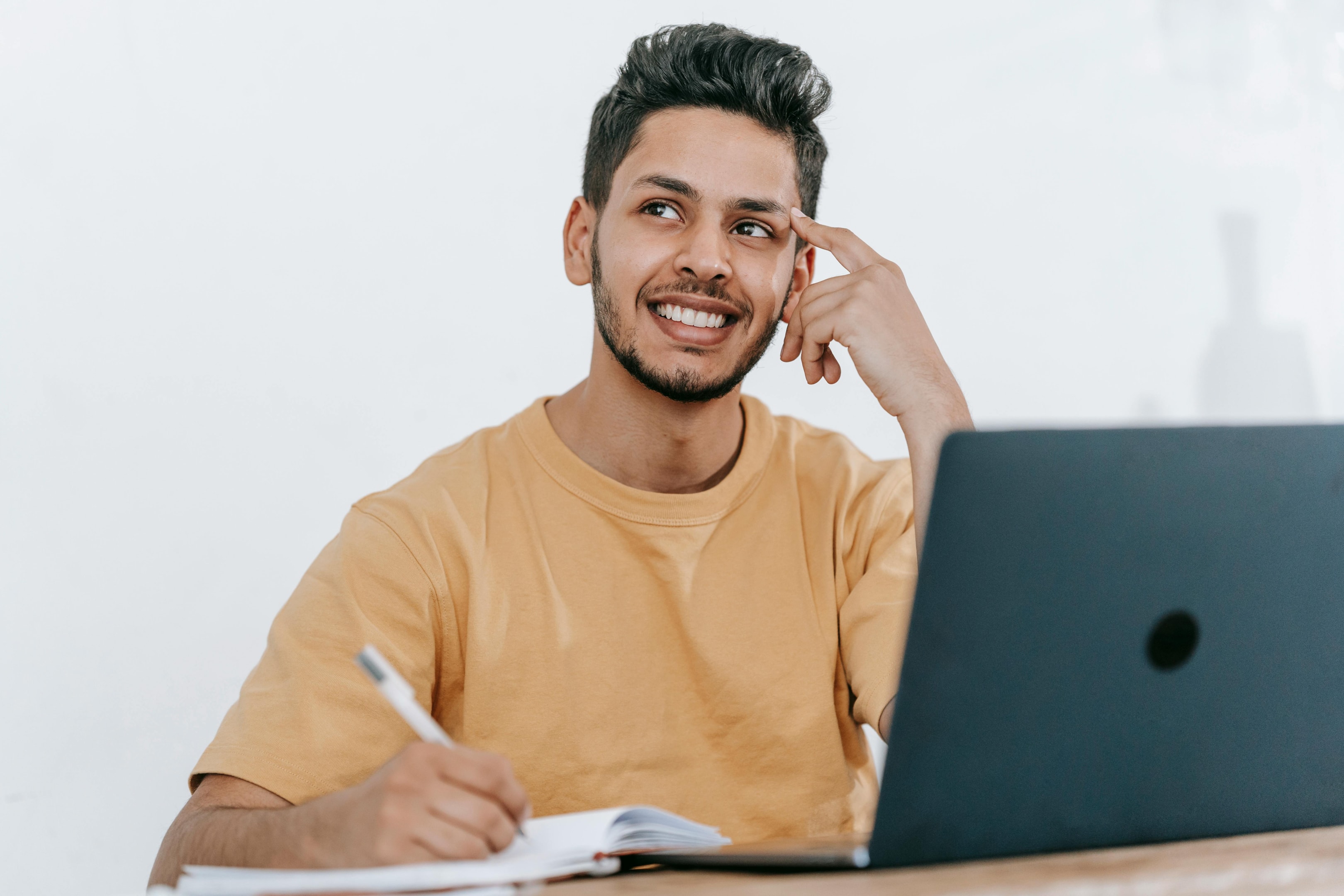 Happy man in front of a laptop and a notebook creating a financial plan