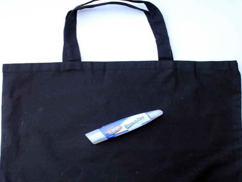 Bleach pen against a dark canvas tote bag