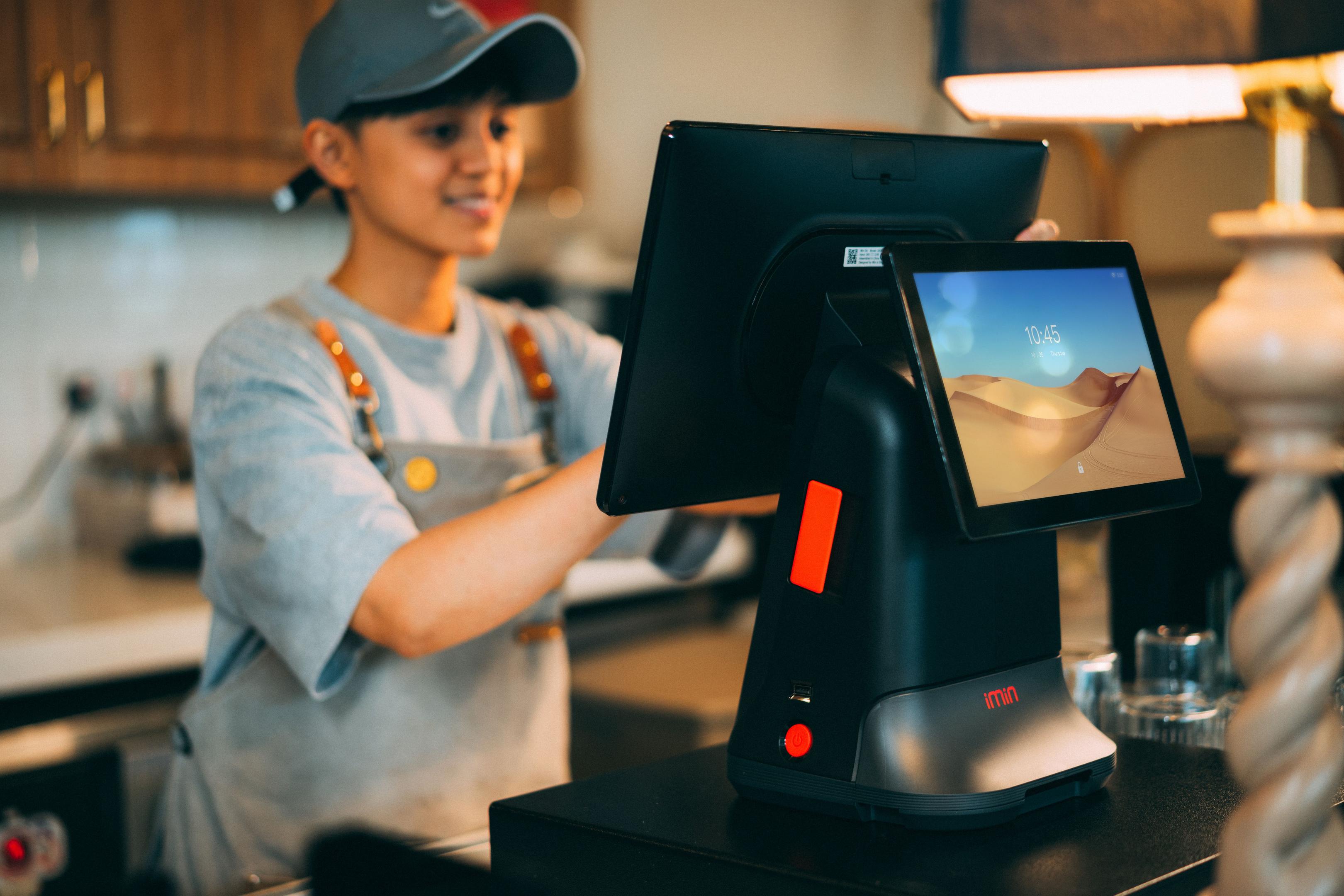 The image shows a restaurant host stand featuring a phone, tablet, and POS terminal neatly arranged on the counter, symbolizing effective restaurant management and streamlined operations. This setup is essential for managing restaurant staff and ensuring excellent customer service in the food service industry.