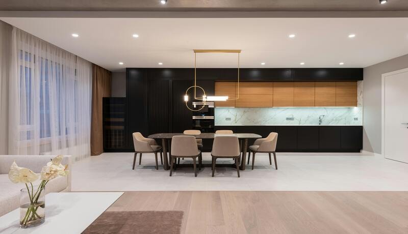 Modern kitchen and dining area with ceiling-mounted lights illuminating the walls and cabinetry.