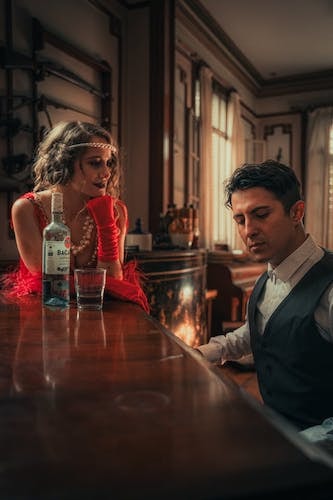 Woman enjoying craft cocktails in a cozy atmosphere while admiring the playing of the man at the piano; completing the vibe