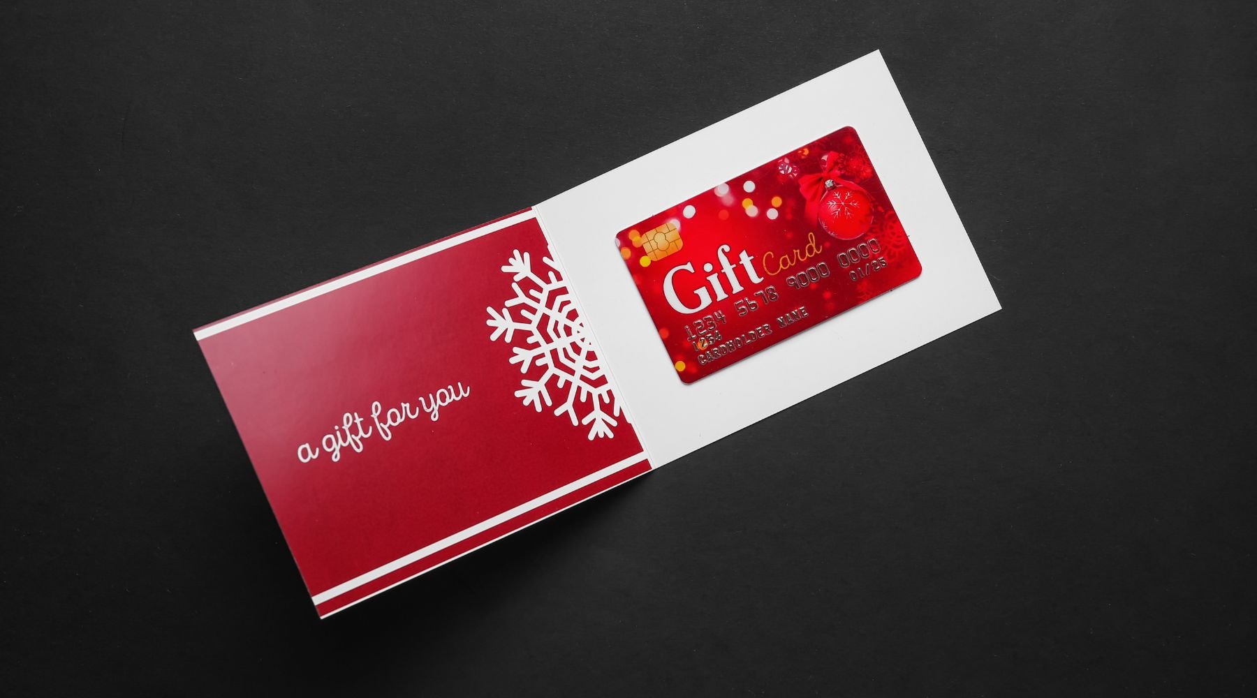 Red holiday-themed gift card next to a greeting card with a snowflake design.