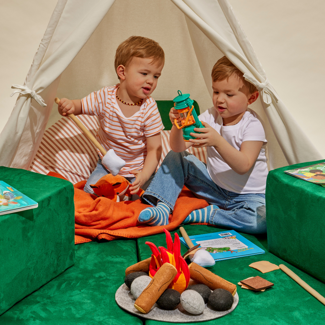Two toddler boys playing over a pretend campfire in a Figgy fort
