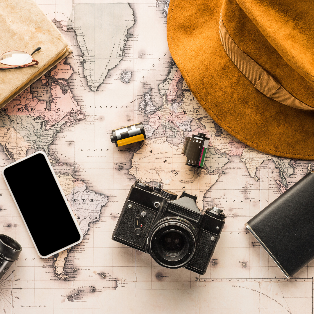 old map with camera, phone, glasses, rolls of film, and hat