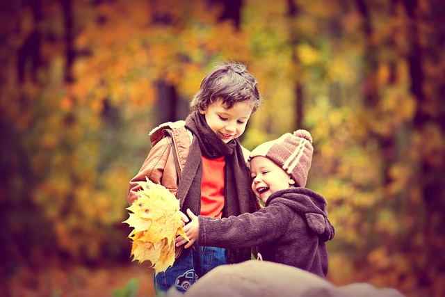 Dziecko na jesiennym spacerze w parku z rodzeństwem podczas zabawy