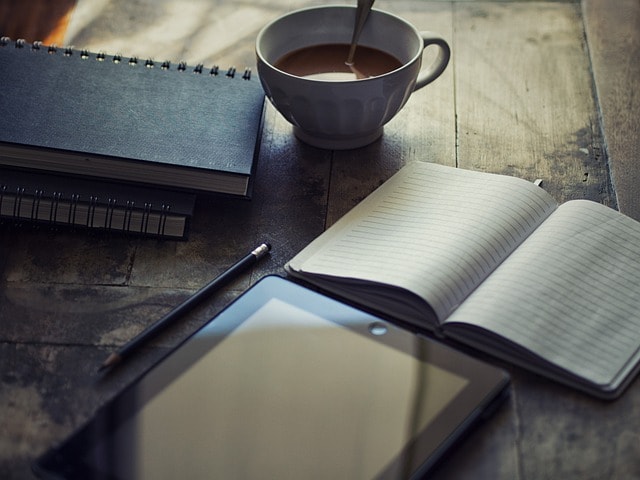 A notebook, a cup of tea and a pen representing creative writing.