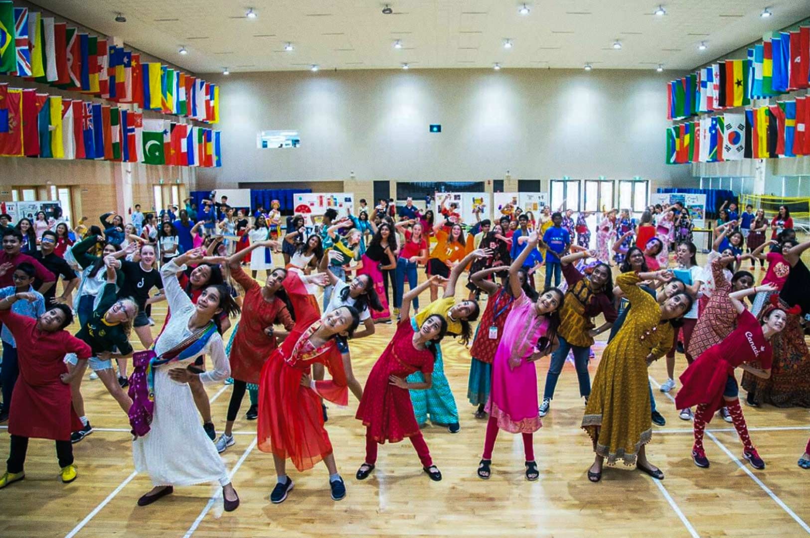 Large cultural dance event with children performing in colorful traditional outfits.