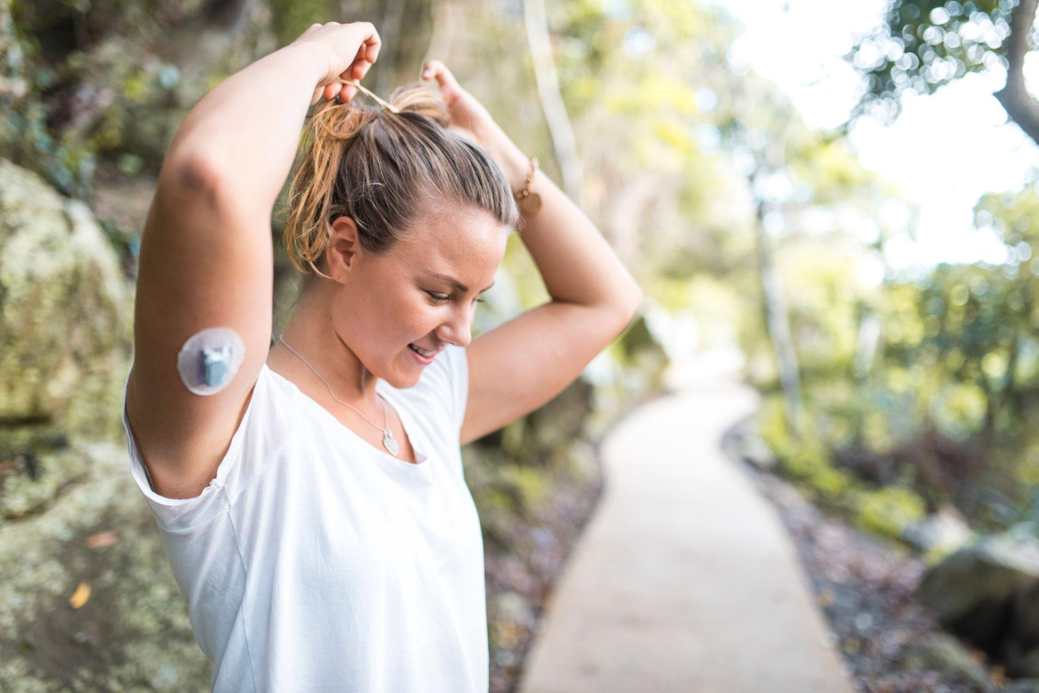 A person wearing a continuous glucose monitoring device on their arm to track high glucose event without skin irritation.