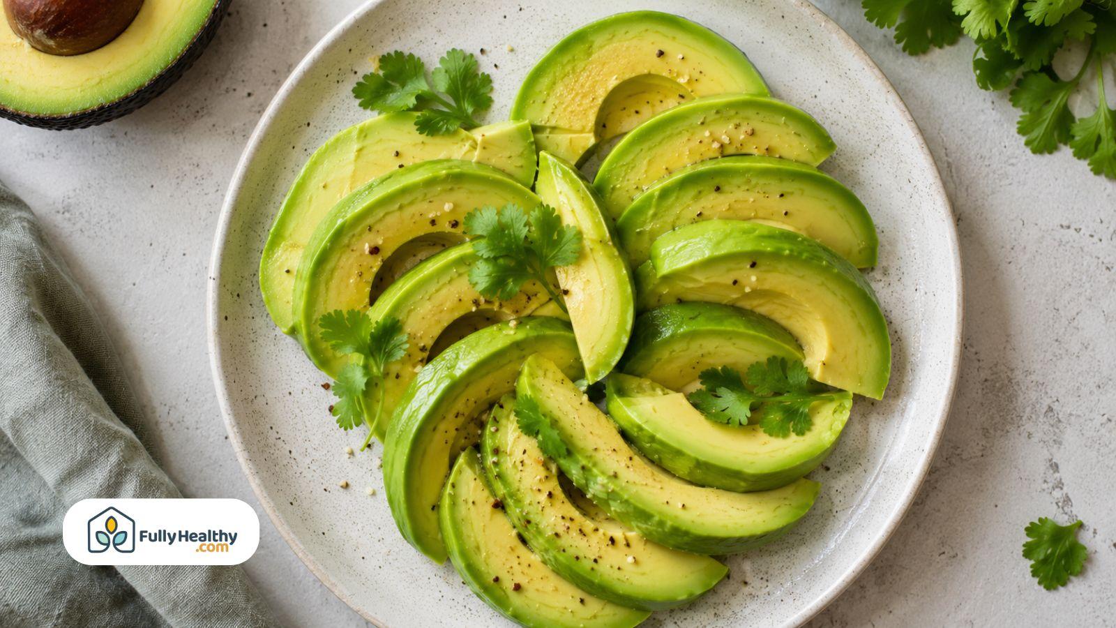 Sliced avocado arranged on a plate with herbs and black pepper seasoning.